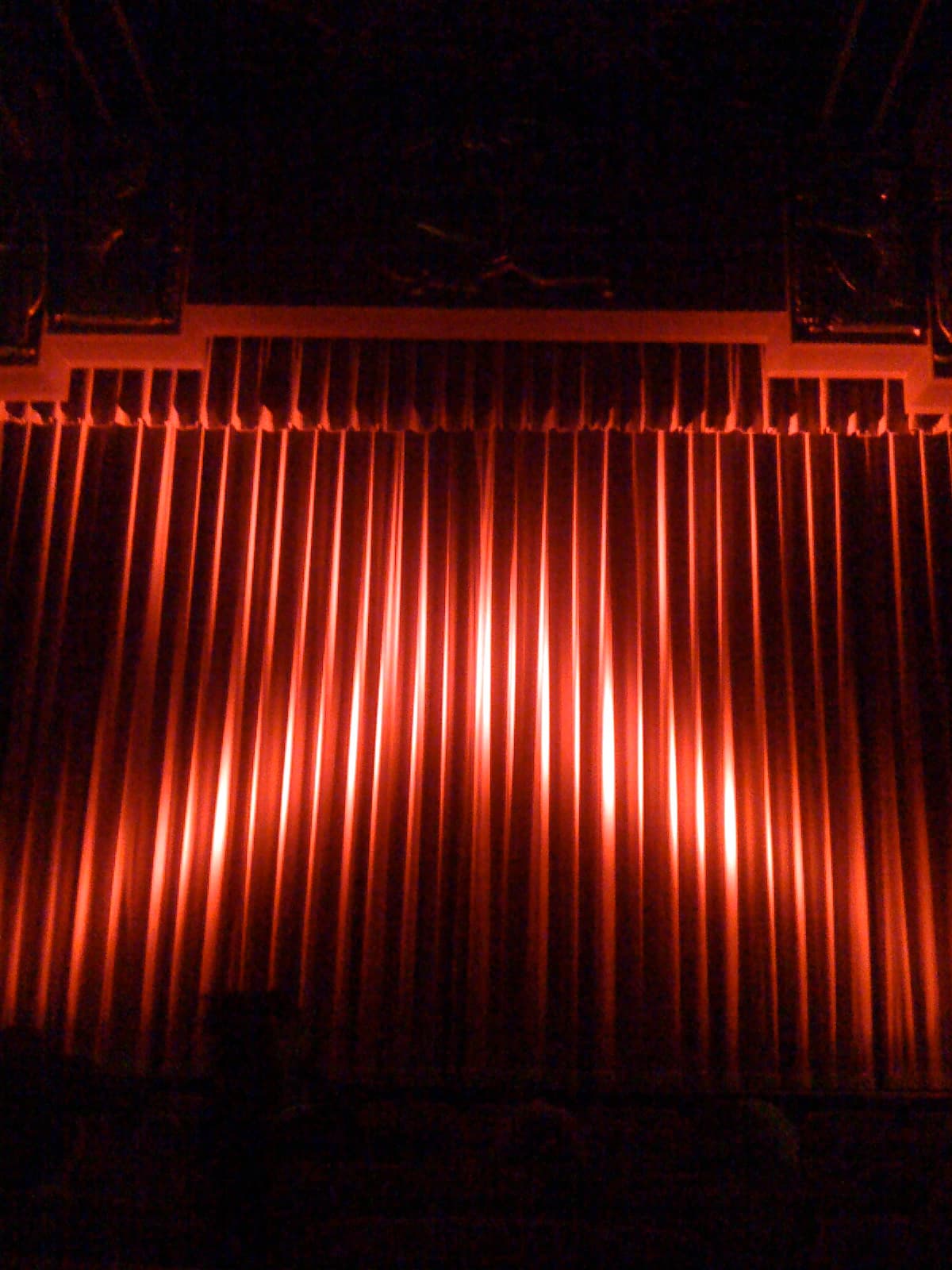 A closed red stage curtain at a historic theater.